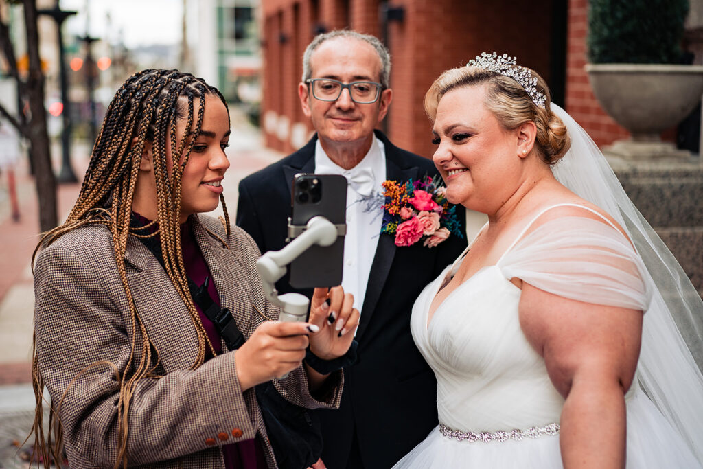 Bride and groom smiling as they watch behind-the-scenes footage captured by their wedding content creator.